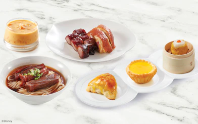 Dim sum platter with noodles, roasted meats, and desserts at Disneyland Hong Kong.
