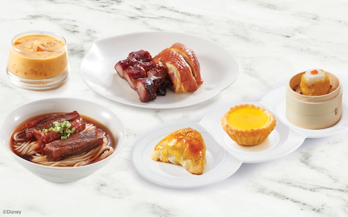 Dim sum platter with noodles, roasted meats, and desserts at Disneyland Hong Kong.