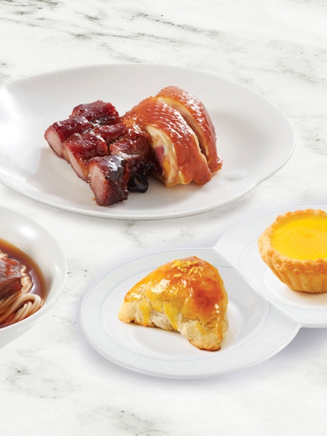 Dim sum platter with noodles, roasted meats, and desserts at Disneyland Hong Kong.
