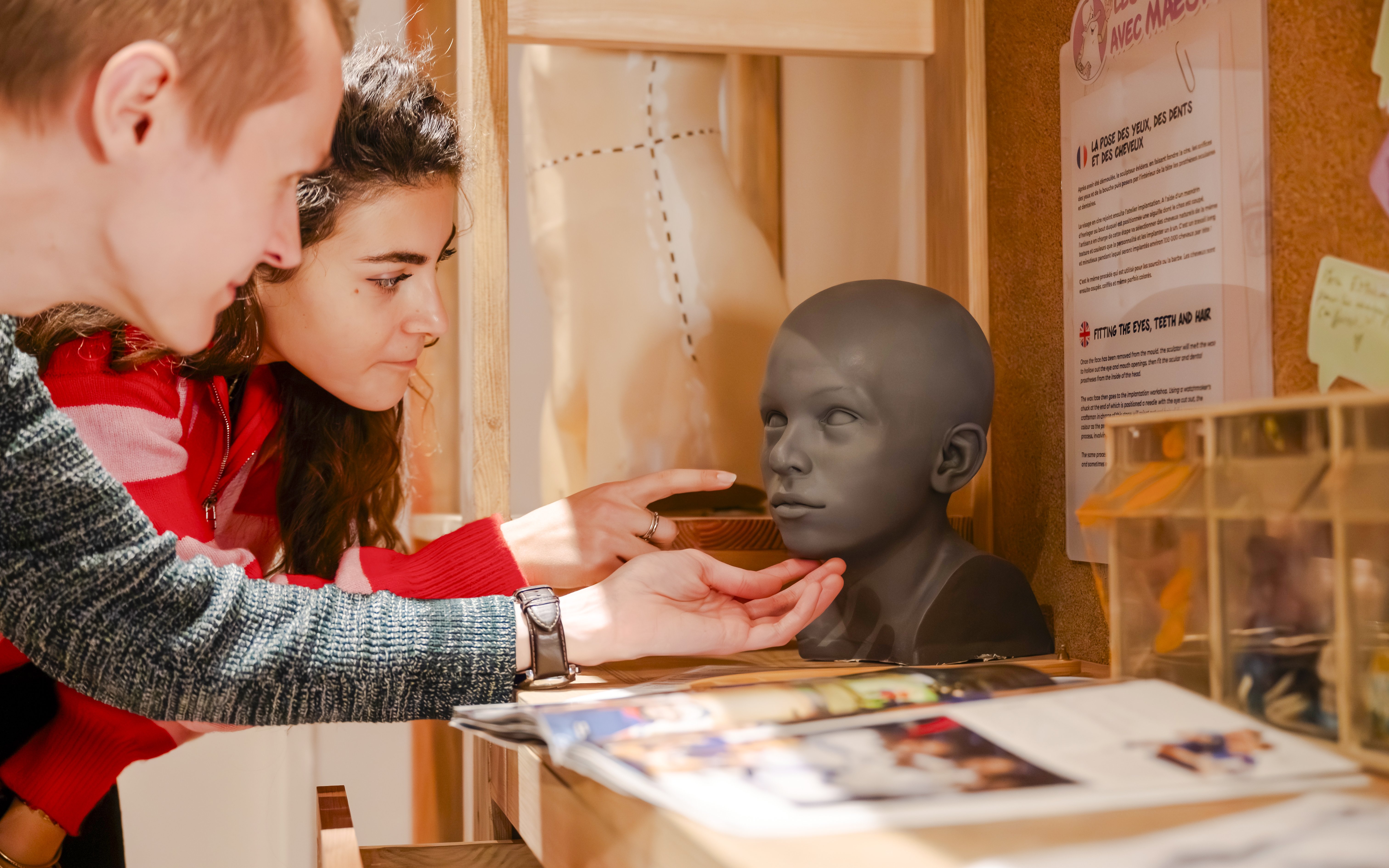 Visitors examining a wax head model at Grévin Paris Wax Museum.