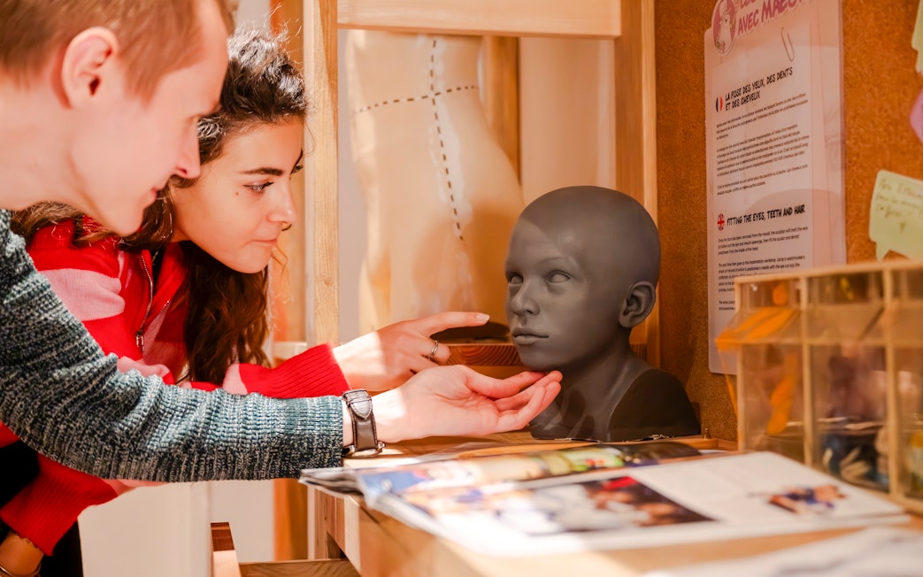Visitors examining a wax head model at Grévin Paris Wax Museum.