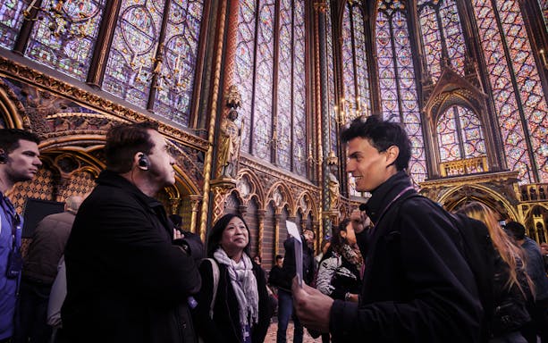 Tour group inside Sainte-Chapelle, Île de la Cité, admiring stained glass windows.
