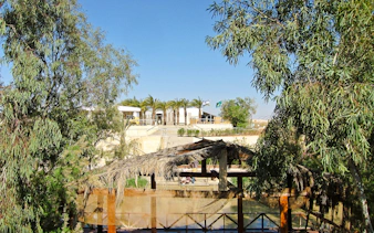 Bethany Beyond the Jordan site with wooden structure and trees, part of Amman full-day tour.