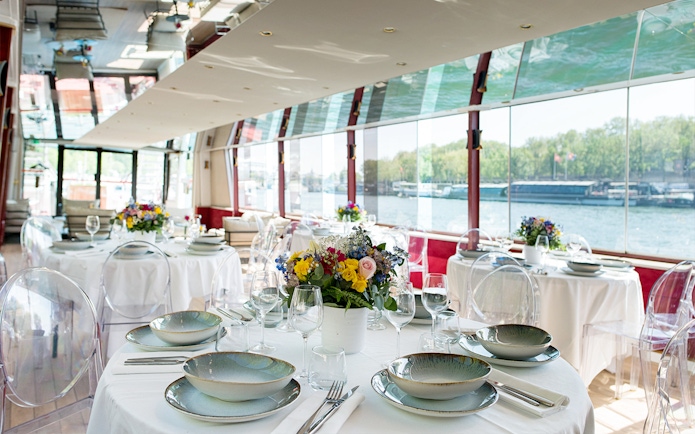 Elegant dining setup on a Parisian boat cruise with river views.