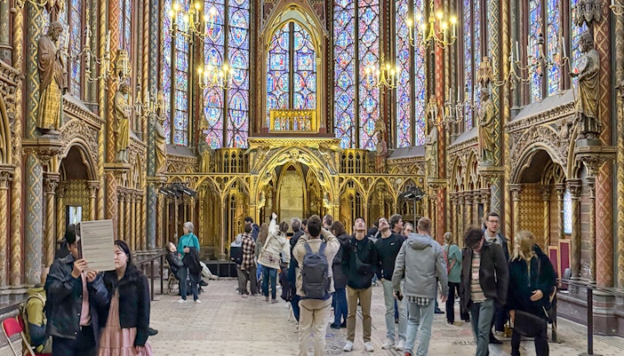 Tourists exploring the stunning interior of Sainte Chapelle, Paris, with their entry tickets, showcasing the unique stained glass windows and gothic architecture