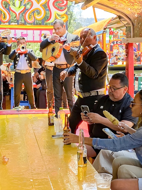 Guests enjoying mariachi band on Trajinera Party boat in Xochimilco, Mexico.