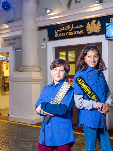 Children in security uniforms at KidZania Dubai near Dubai Customs exhibit.
