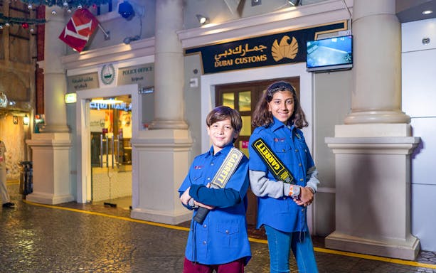 Children in security uniforms at KidZania Dubai near Dubai Customs exhibit.