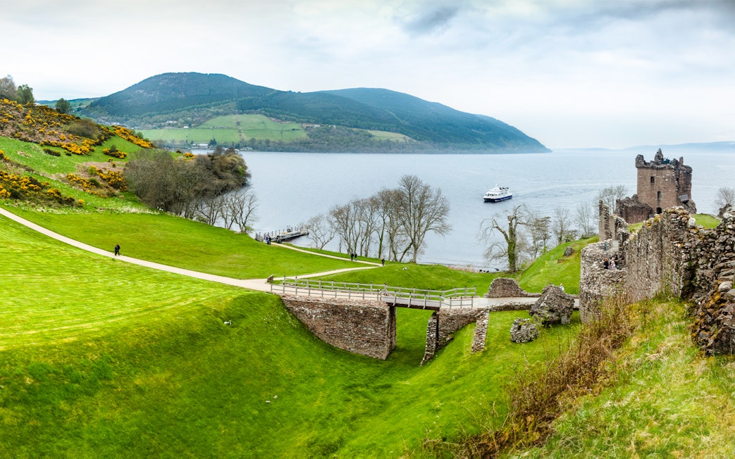 Loch Ness with Urquhart Castle ruins and a boat on the water, Scotland.