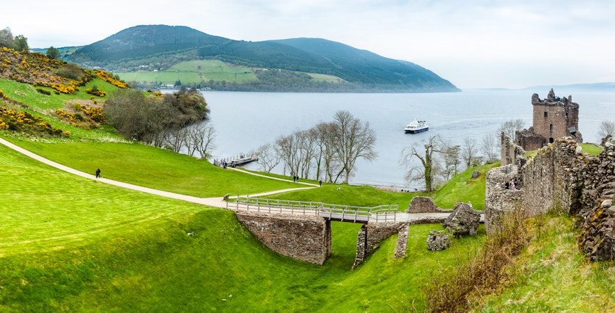 Loch Ness with Urquhart Castle ruins and a boat on the water, Scotland.