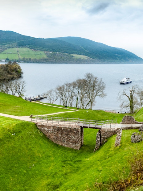 Loch Ness with Urquhart Castle ruins and a boat on the water, Scotland.
