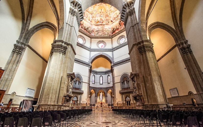 Florence Duomo interior with frescoed dome and rows of chairs.