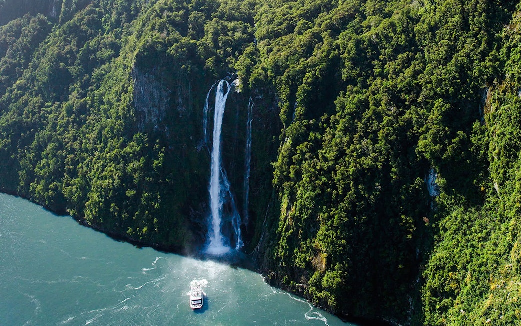Cruise boat near Stirling Falls in Milford Sound, Fiordland National Park, New Zealand.