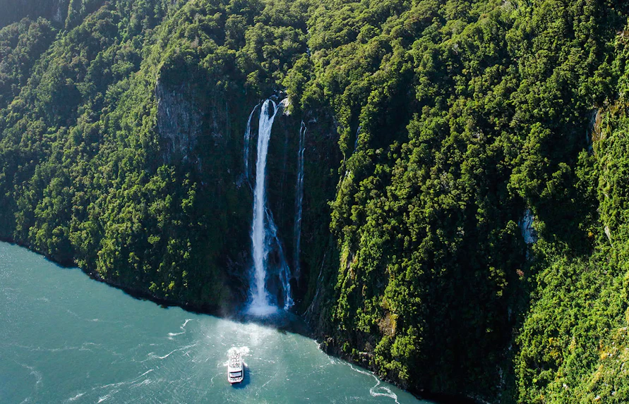 Cruise boat near Stirling Falls in Milford Sound, Fiordland National Park, New Zealand.