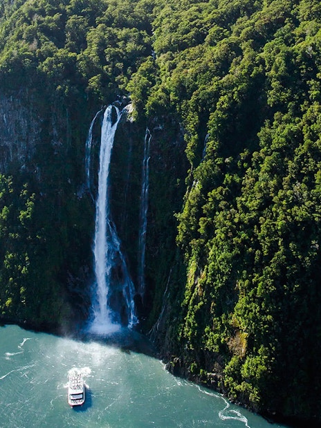 Cruise boat near Stirling Falls in Milford Sound, Fiordland National Park, New Zealand.