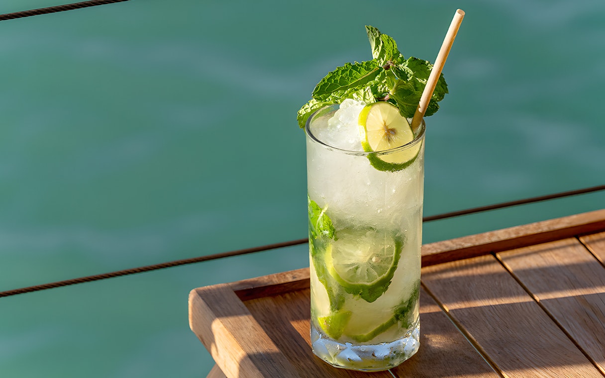 Refreshing cocktail on Yona Beach Club terrace, Phuket, overlooking the sea.