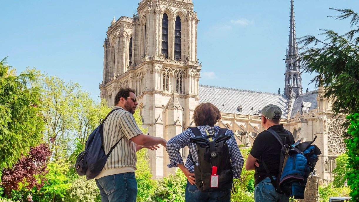 Tourists observing Notre-Dame Cathedral from Île de la Cité during a guided tour.
