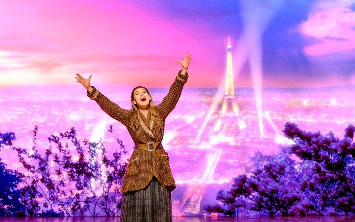 Performer on stage with Eiffel Tower backdrop in Anastasia theatre act.