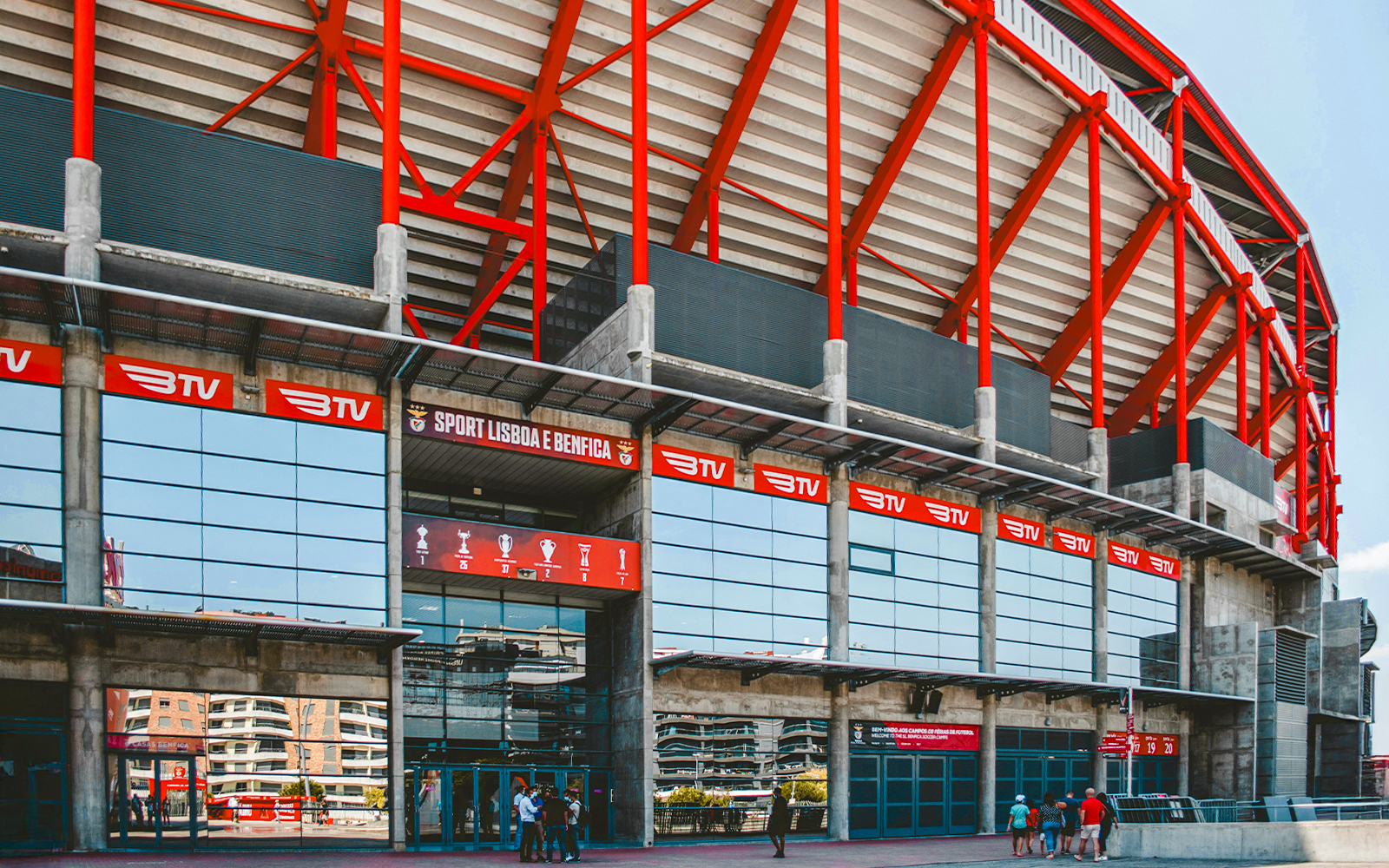 Benfica Stadium entrance with red beams and glass facade in Lisbon, Portugal.