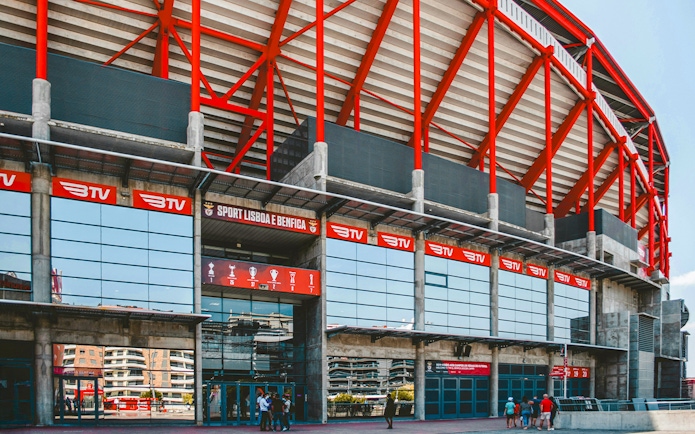 Benfica Stadium entrance with red beams and glass facade in Lisbon, Portugal.