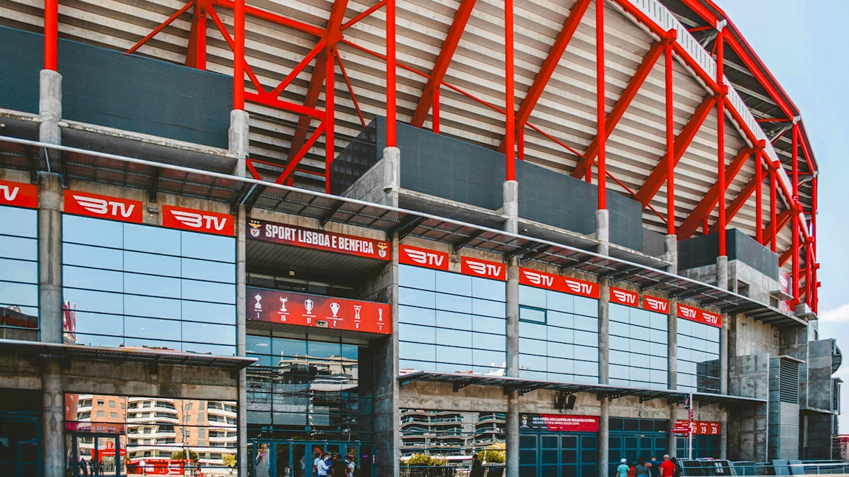Benfica Stadium entrance with red beams and glass facade in Lisbon, Portugal.