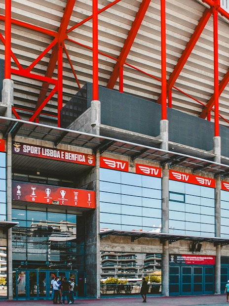 Benfica Stadium entrance with red beams and glass facade in Lisbon, Portugal.