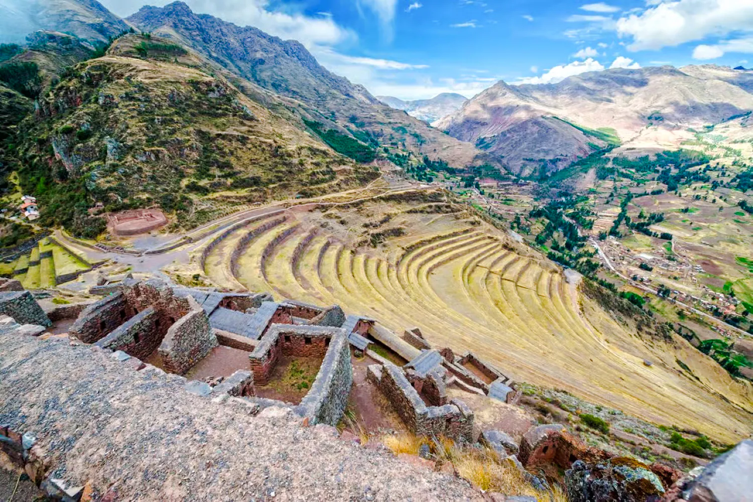 Terraced fields and ruins in Sacred Valley, Peru, with mountains in the background.