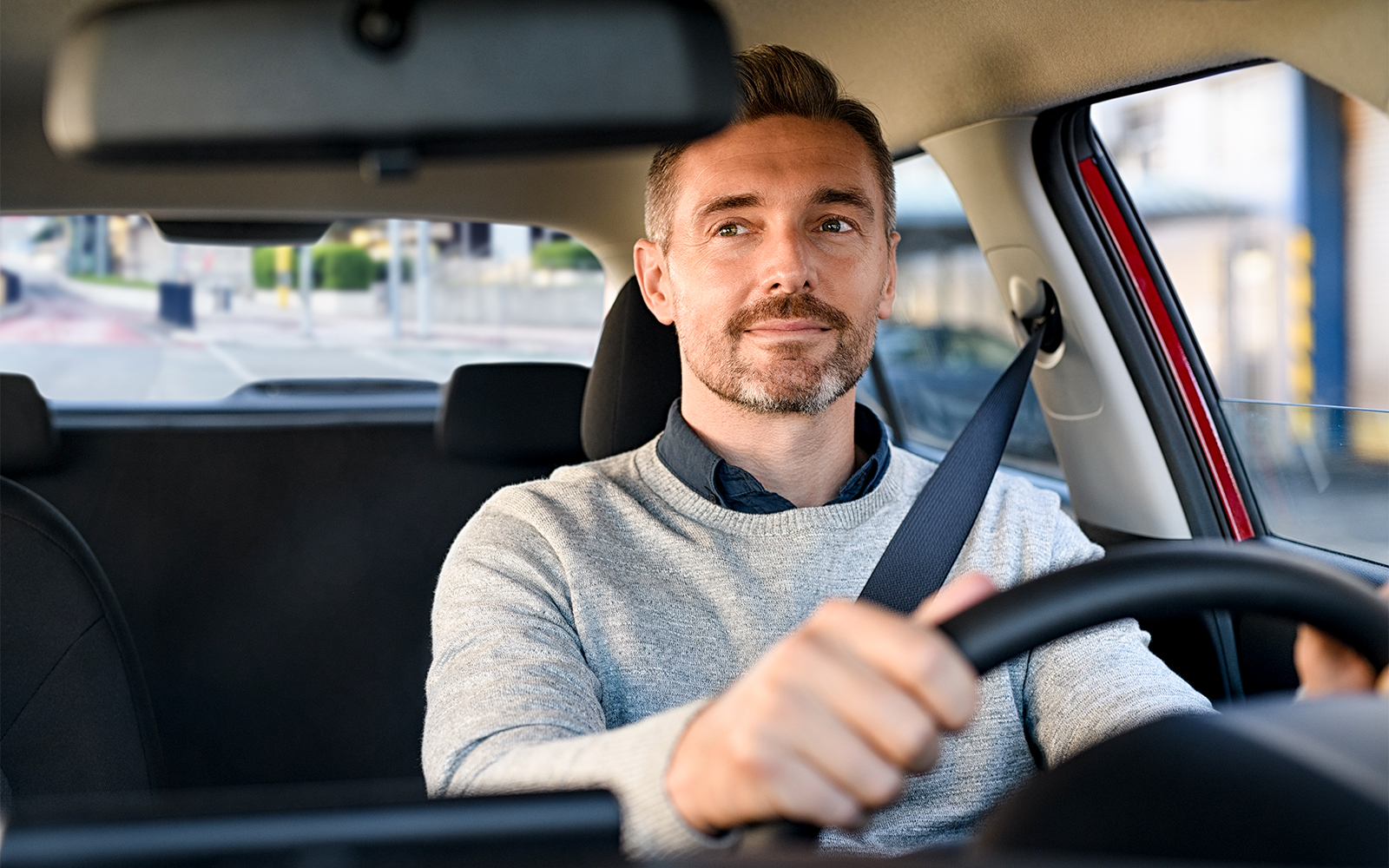 Man driving a car on a city street.