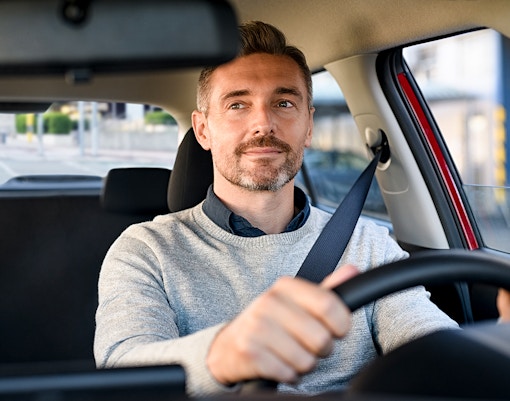 Man driving a car on a city street.