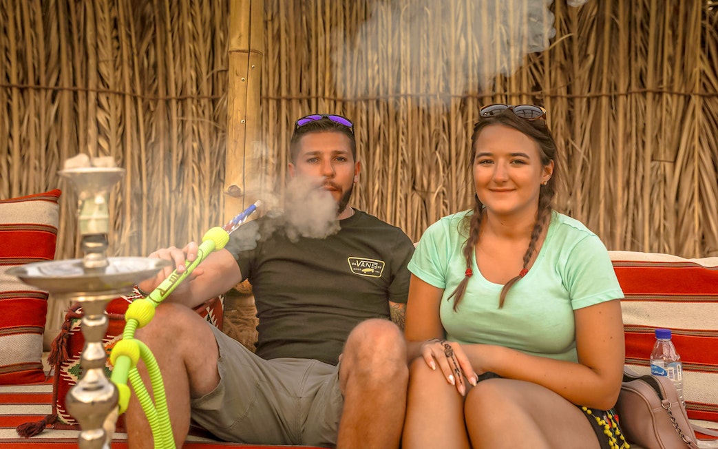 Couple enjoying hookah during Abu Dhabi desert safari.