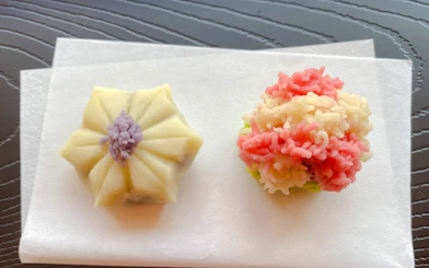 Japanese traditional sweets on paper, featuring a floral-shaped wagashi and a colorful nerikiri.