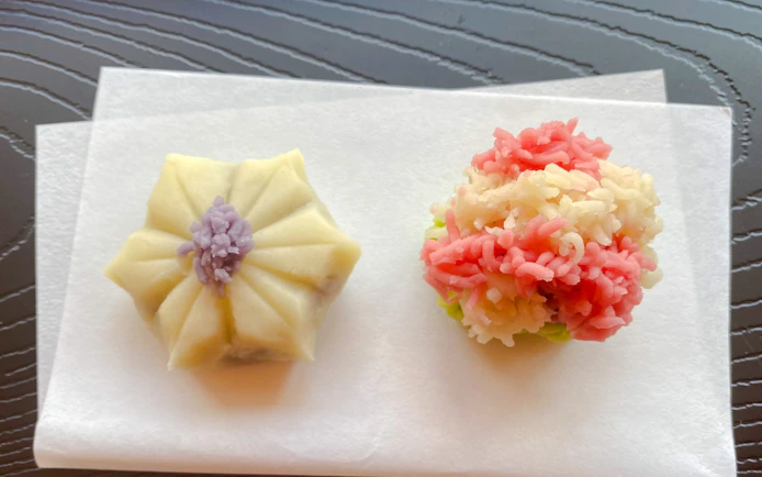 Japanese traditional sweets on paper, featuring a floral-shaped wagashi and a colorful nerikiri.