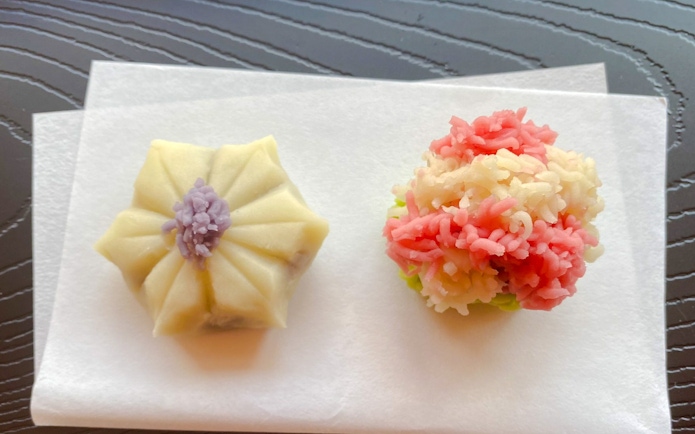 Japanese traditional sweets on paper, featuring a floral-shaped wagashi and a colorful nerikiri.