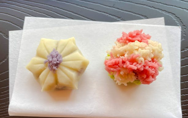 Japanese traditional sweets on paper, featuring a floral-shaped wagashi and a colorful nerikiri.