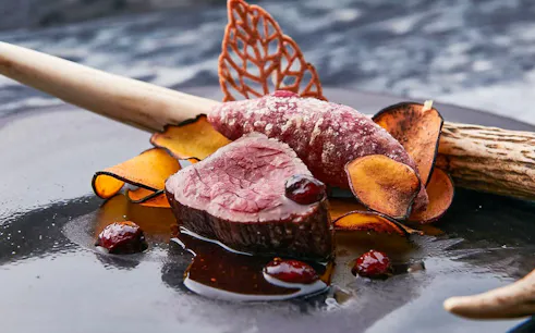 Wagyu beef with garnishes on a plate, part of a special course featuring hot pot dishes.