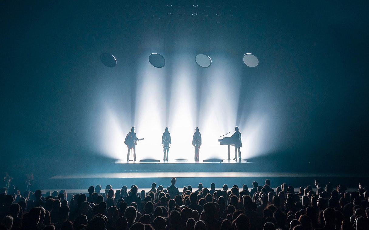 Silhouetted performers on stage with audience at ABBA Voyage show in London.