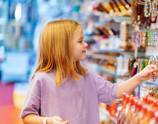 Child exploring colorful bracelets at Museum of Illusions Madrid gift shop.