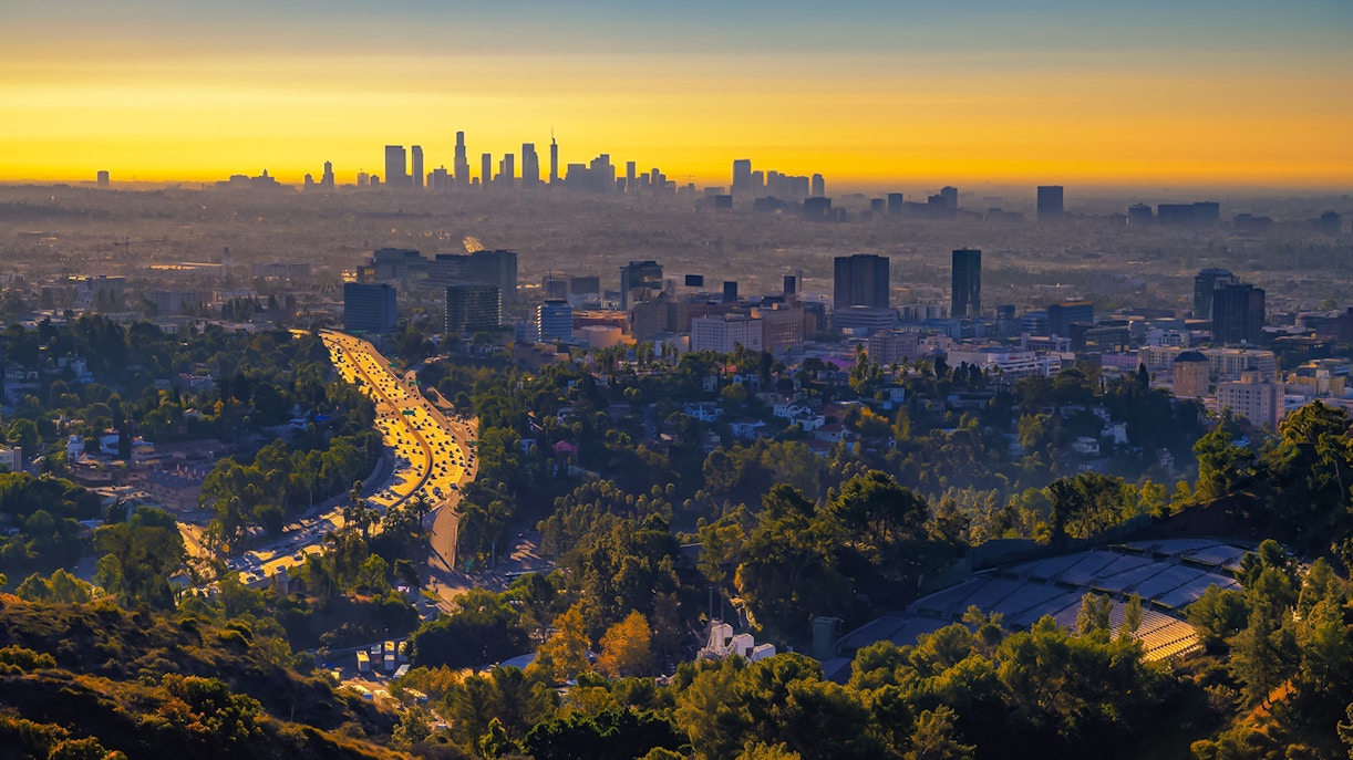 Sunset view of Los Angeles skyline with Hollywood Bowl in foreground.