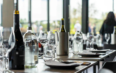Table set for wine tasting with glasses, wine bottles, and plates.