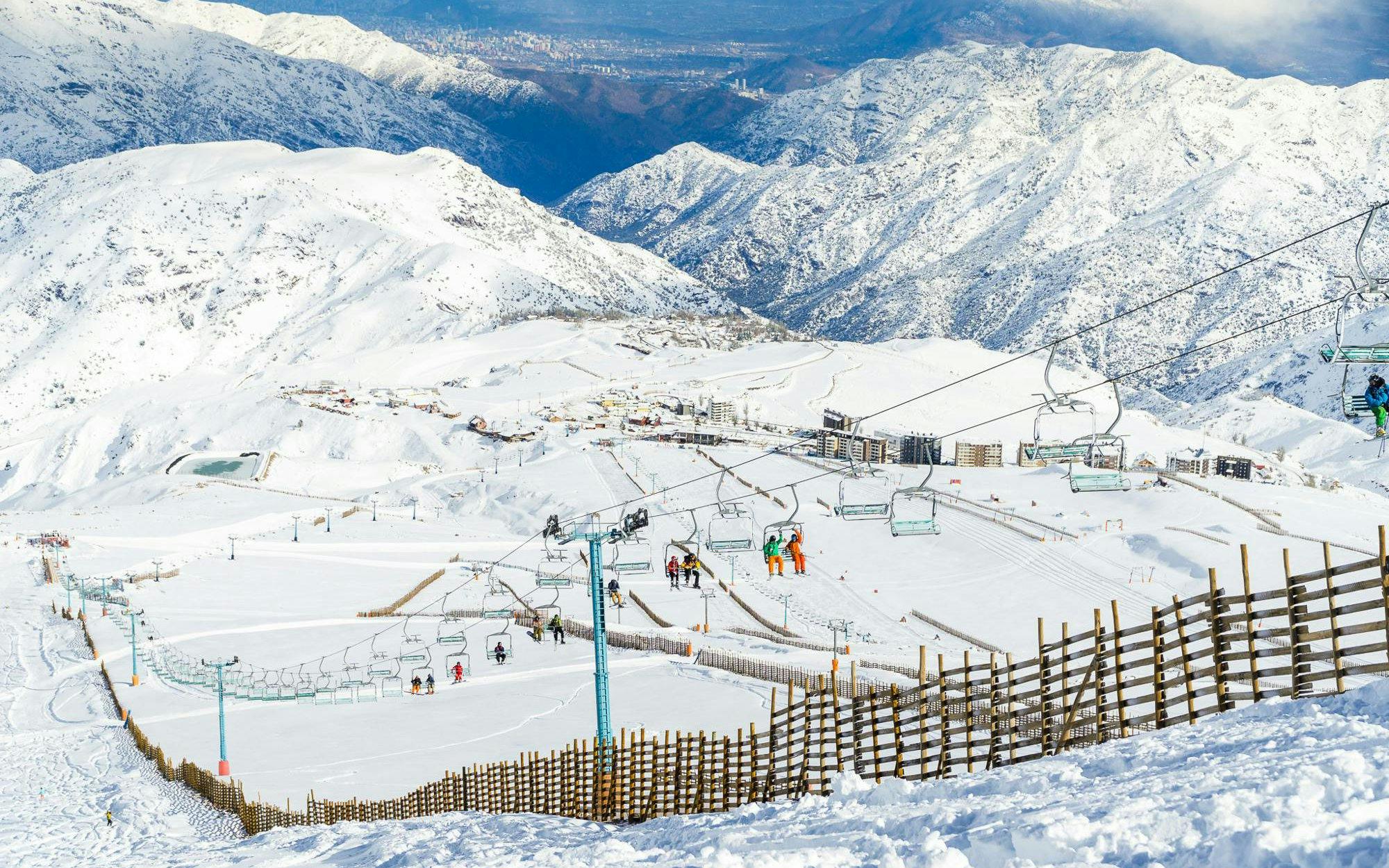 Ski lift ascending snowy slopes at Farellones Ski with mountain backdrop.