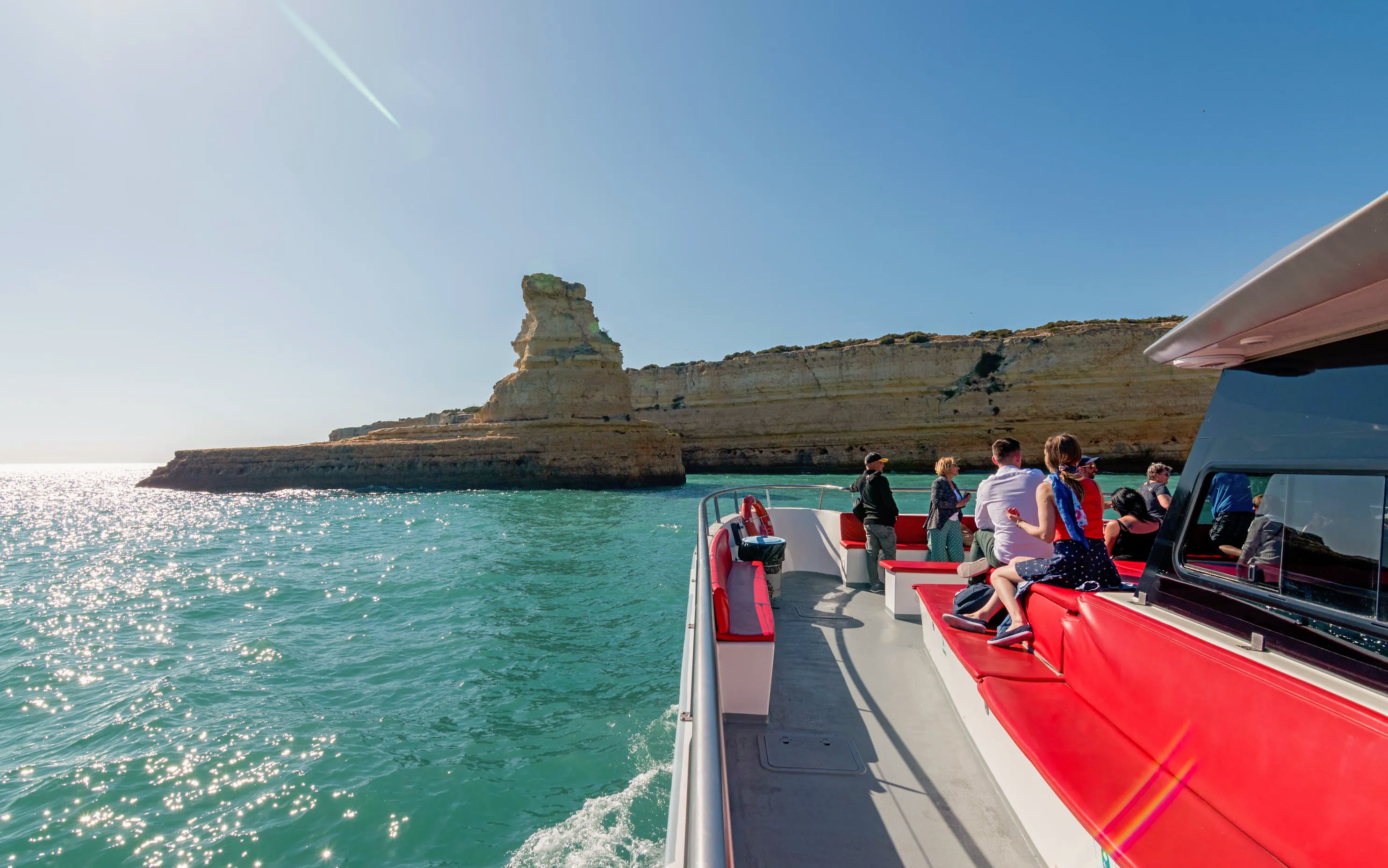 Boat tour along the Benagil Caves coastline with passengers enjoying the view.