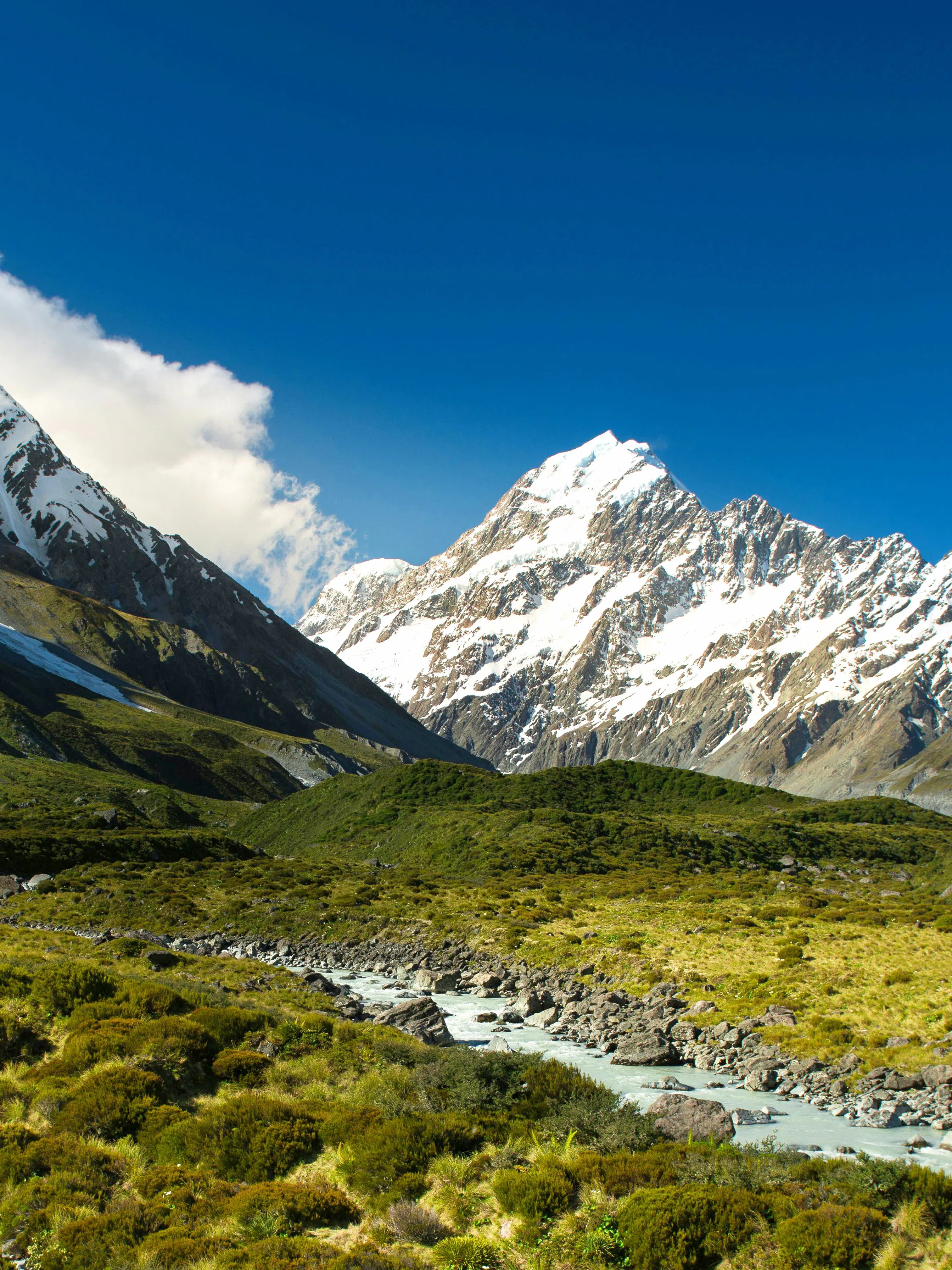 Mount Cook with snow-capped peaks and a river in New Zealand landscape.
