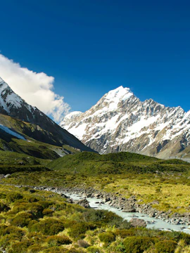 Mount Cook with snow-capped peaks and a river in New Zealand landscape.
