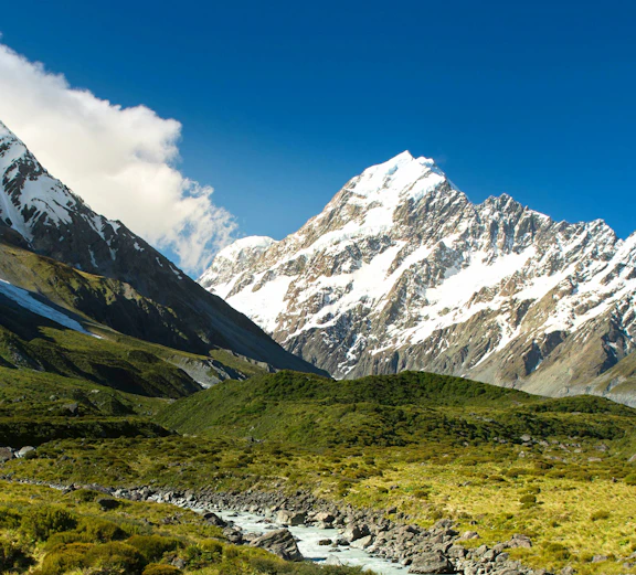 Mount Cook with snow-capped peaks and a river in New Zealand landscape.