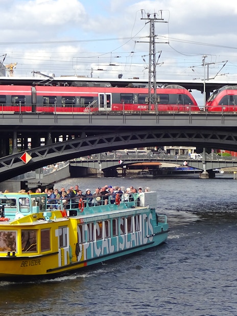 Sightseeing cruise boat on the Spree River in East Berlin passing under a railway bridge.