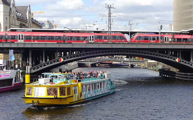 Sightseeing cruise boat on the Spree River in East Berlin passing under a railway bridge.