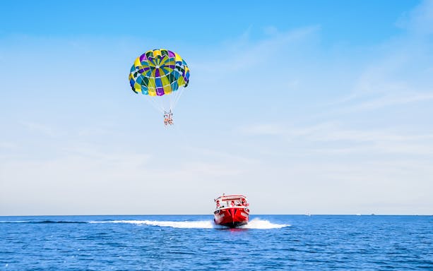 Parasailing over the ocean in Dubai with colorful parachute and speedboat.
