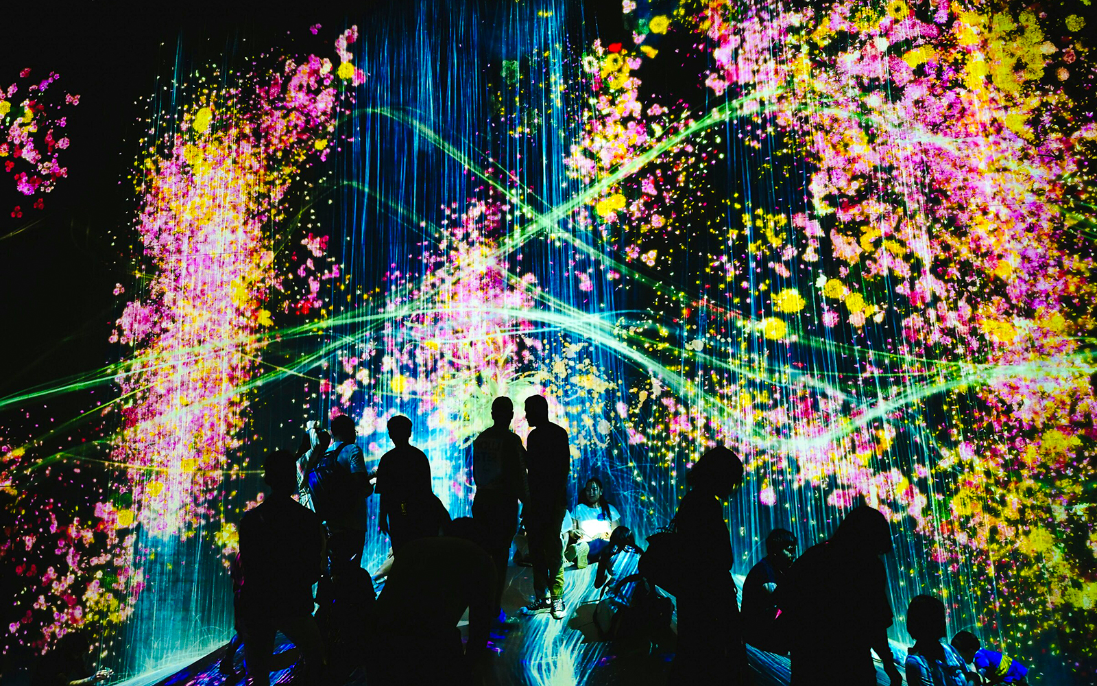 Visitors at TeamLab Kyoto surrounded by vibrant digital art installations.