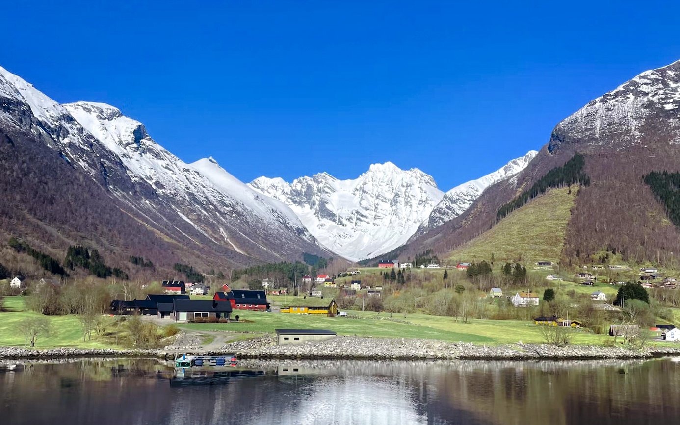 Hjørundfjord landscape with snow-capped mountains and village, Norway.