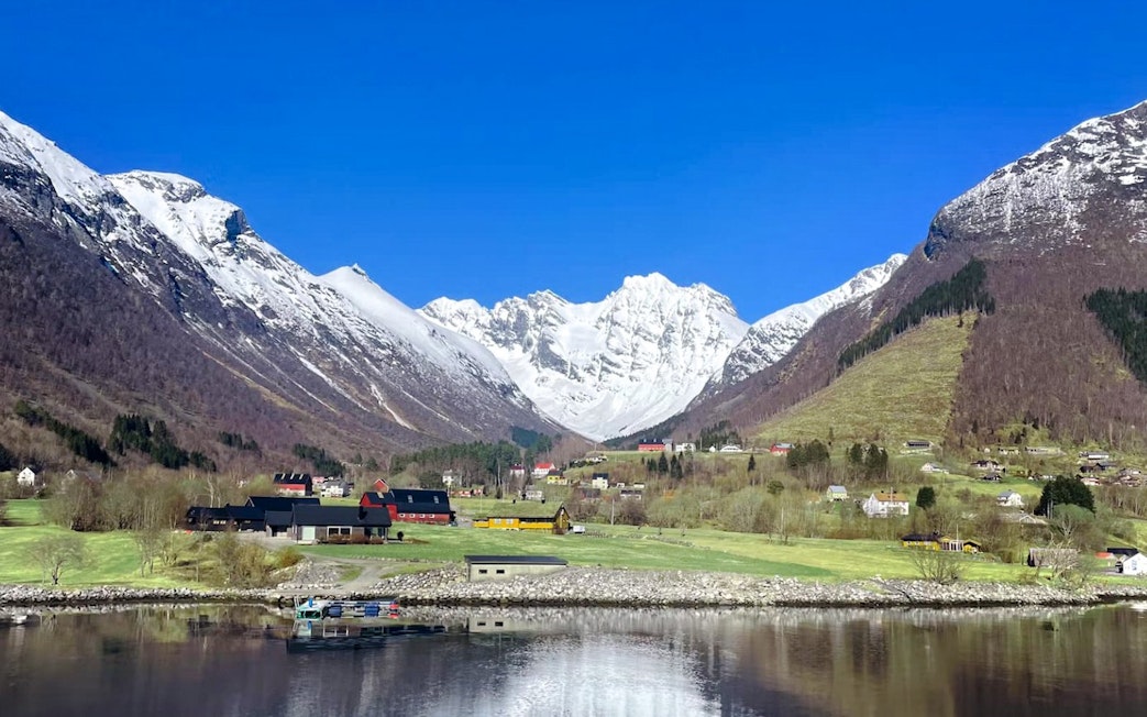 Hjørundfjord landscape with snow-capped mountains and village, Norway.